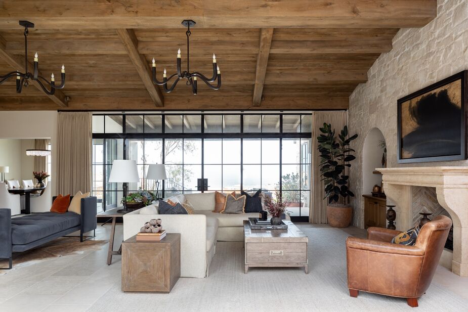 Walls of windows look out onto the surrounding terraced neighborhood and the Pacific Ocean. The framed artwork above the antique-inspired fireplace surround disguises the TV; the rug subtly delineates this portion of the great room from the rest. Find a similar sectional here and a similar console table here.
