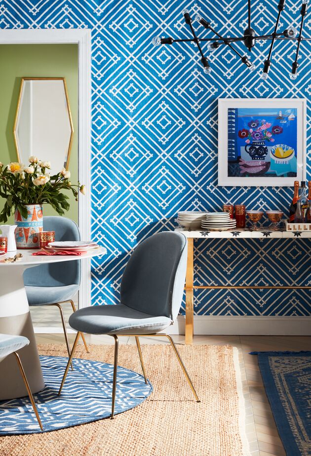 The fanciful wallpaper adds unexpected Palm Beach whimsy to the sleek Mid-Century Modern lines of the pedestal table, the splay-legged chairs, and the linear chandelier. Find the framed artwork, Mixed Anemones and Lemons by Emma Williams, here, and the mirror here. 
