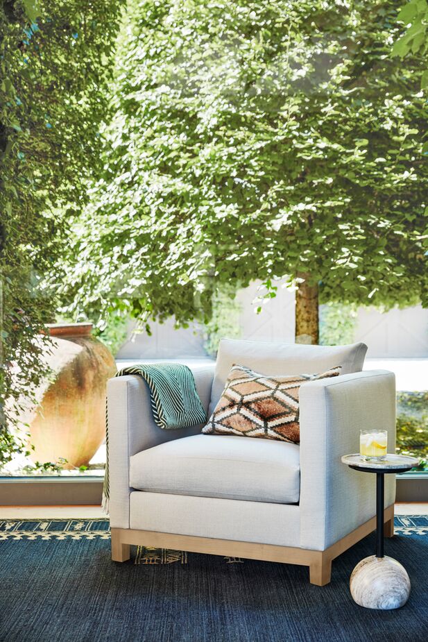 The addition of a tawny velvet pillow and the Sasha Monogram Throw to the Delano Performance Linen Chair in Almond makes this an early-autumn vignette. Find the rug here and the side table here. Photo by Joe Schmelzer. 
