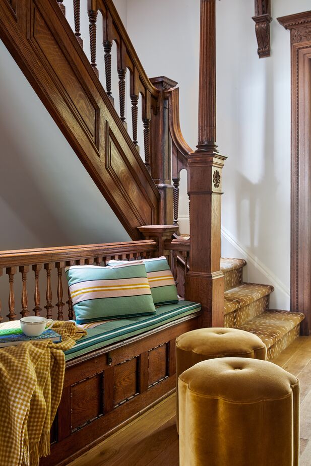 The cushions of the second floor’s built-in landing seat are covered in the same stripes as the living room’s cocktail ottoman, adding cohesiveness to the home.
