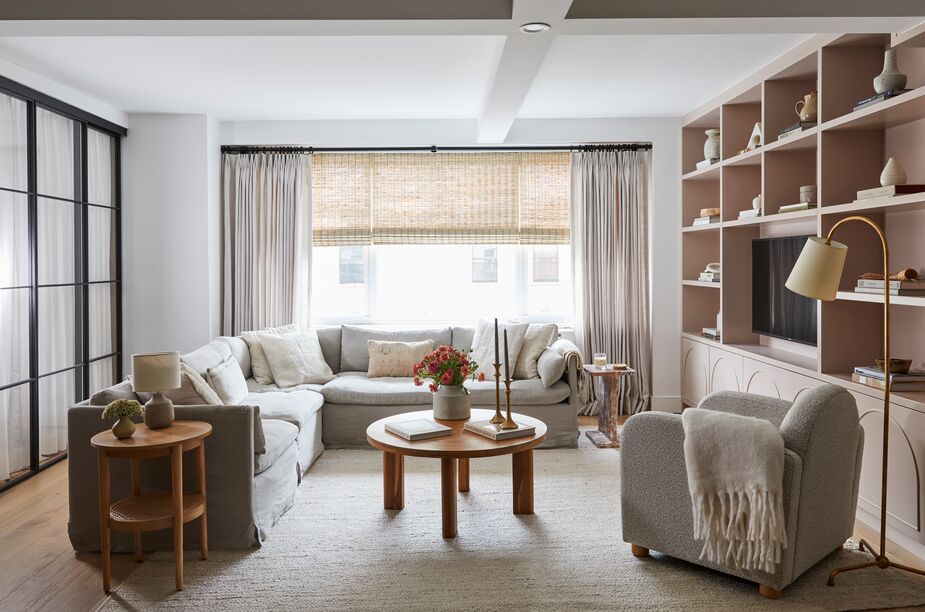 Curves galore, from the arches in the millwork below the shelves to the round tables, offset the living room’s rectangular shape and gridded doors. Find a similar rug here.  
