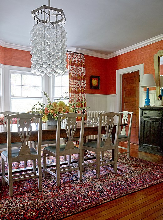 Mele covered two-thirds of the dining room walls with white wainscoting to temper the coral grass cloth that covers the reminder and painted the ceiling a subtle shade of blue.
