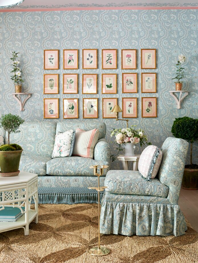 Jessica Kain Barton of J Kathryn Interiors transformed the lower lounge into a floral fantasy. Walls, sofa, and slipper chair are covered in the same lyrical toile, with framed botanical prints, bouquets, and topiaries adding to the theme. The natural-fiber rug helps ground the room, both literally and figuratively (find a similar rug here). 
