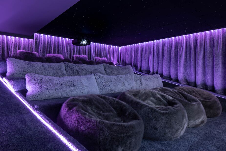 Throughout the home, bold color is limited to artwork—except in the theater room, a cocoon of purple plushness. Benjamin created the room out of an all-but-hidden space off the game room.
