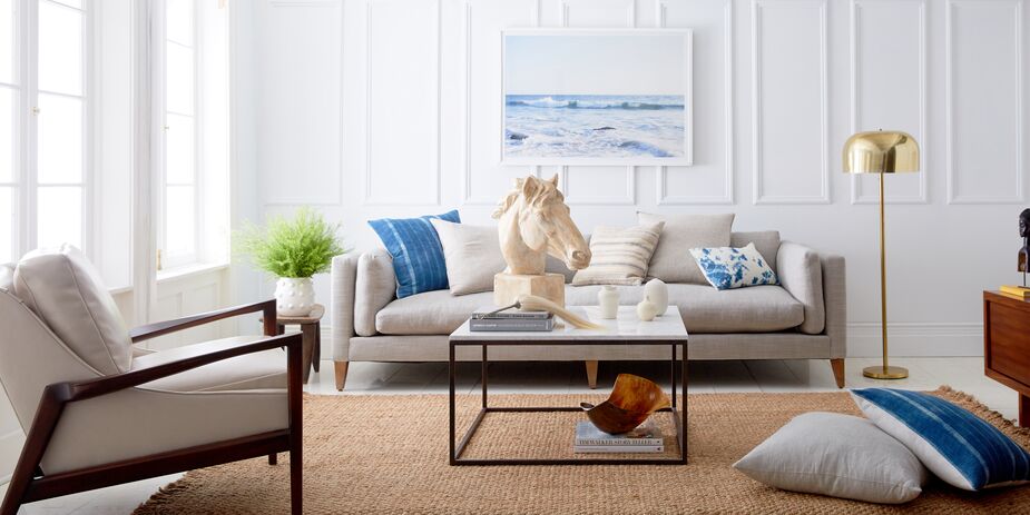 Mid-Century Modern furniture with wood, rather than acrylic or metallic, frames slides right into the Naturalist aesthetic. Opting for pale, neutral upholstery helps too, as with this armchair and sofa. Find a similar rug here and the artwork here.
