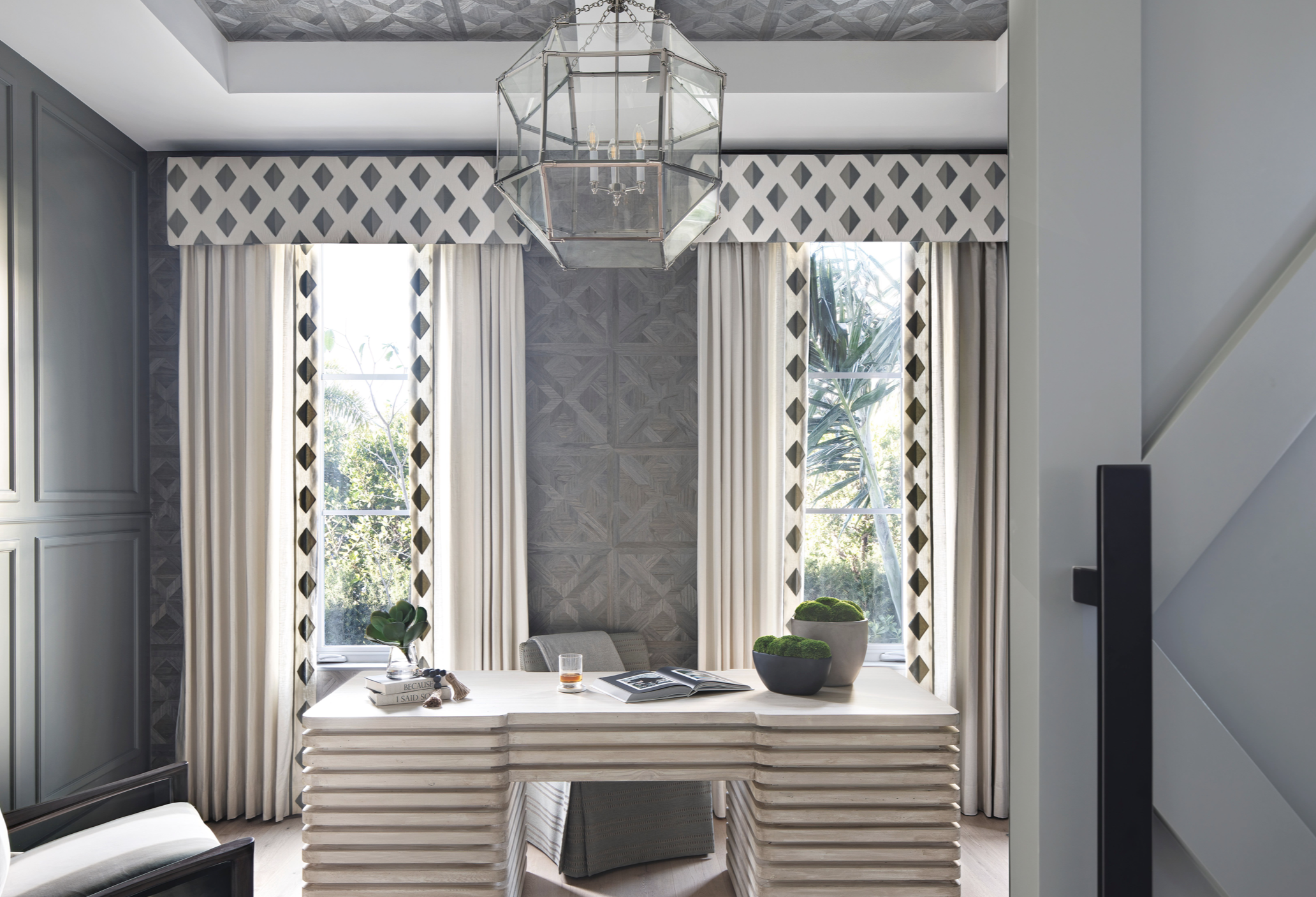 
The home office outfitted in shades of gray is anything but boring, thanks to the unique woodwork and the geometric-print window treatments. The custom desk anchors the room. Find a similar pendant here.

