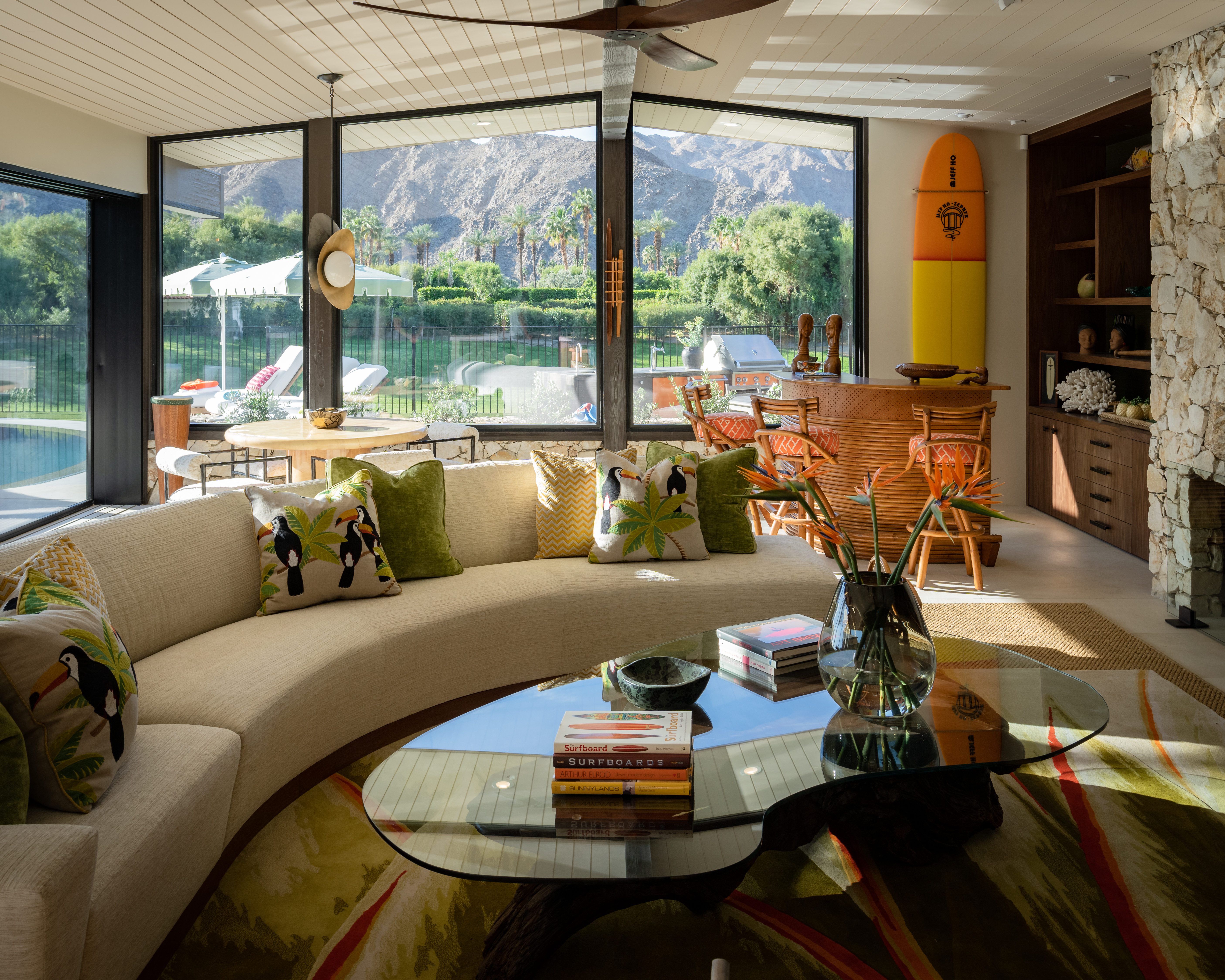 In the family room, Shannon Palmer of Shannon Design used curves galore—the sofa, the cocktail table, the semicircular bar, the round breakfast table—to subtly reference ocean waves. The vintage surfboard is a less-subtle reference. Find a similar ceiling fan here.
