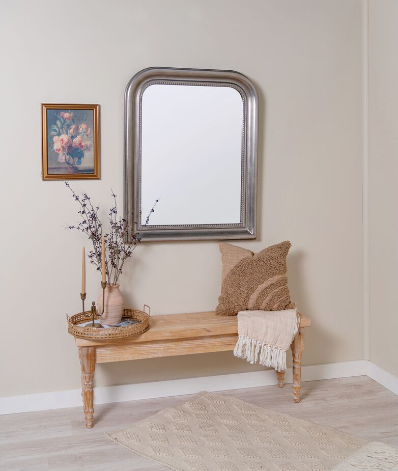 The Mason Wall Mirror in Silver Leaf looks right at home next to a golden frame and above an antique golden candleholder.
