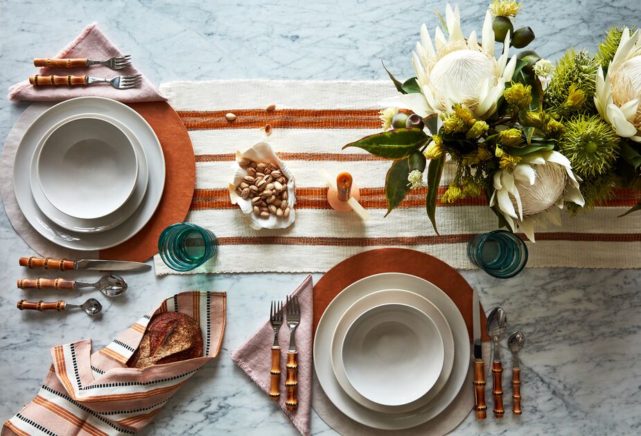 The woven table runner provides a tactile contrast to the sleek marble tabletop, just as the handles of the Bamboo Place Settings do to the smooth Shell Bisque dishware. Photo by Frank Frances.
