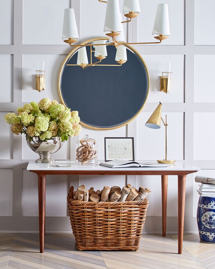 The conical shapes and brass finish of the lighting are MCM-inspired, as is the console table with its acrylic top, wood base, and tapered legs. But they complement the more-traditional furnishings beautifully. Shown above: the Jemma Round Wall Mirror, the Fontaine Large Offset Chandelier, and the Clemente Table Lamp.
