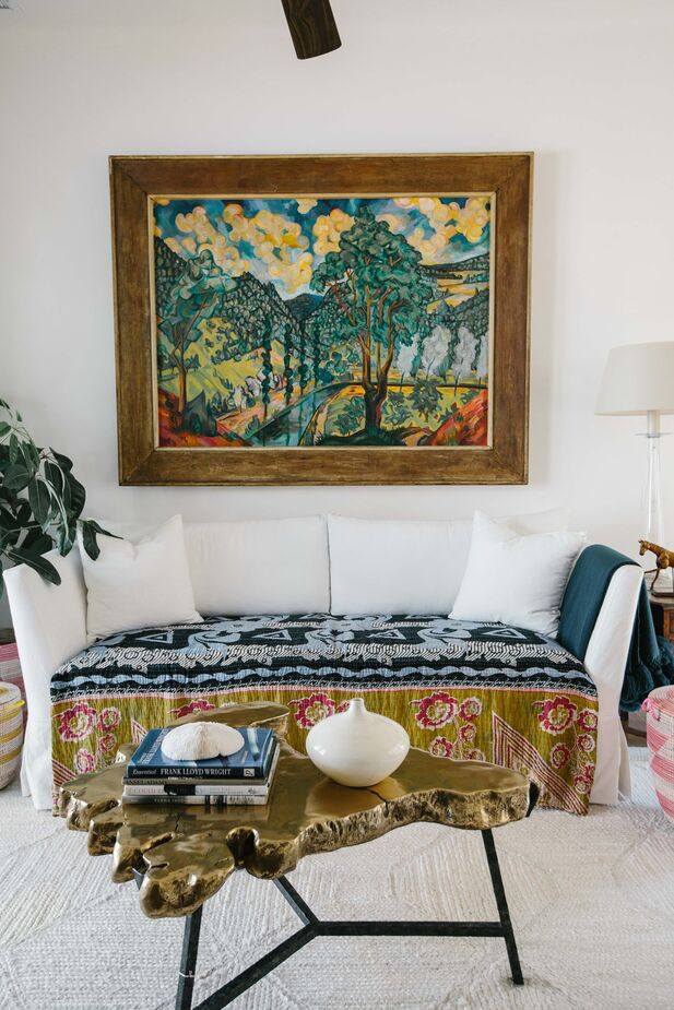In the upstairs den, the vibrant artwork and throw appeal to the client’s love of color, while the neutral walls and rug maintain a sense of serenity. Find a similar coffee table here. 
