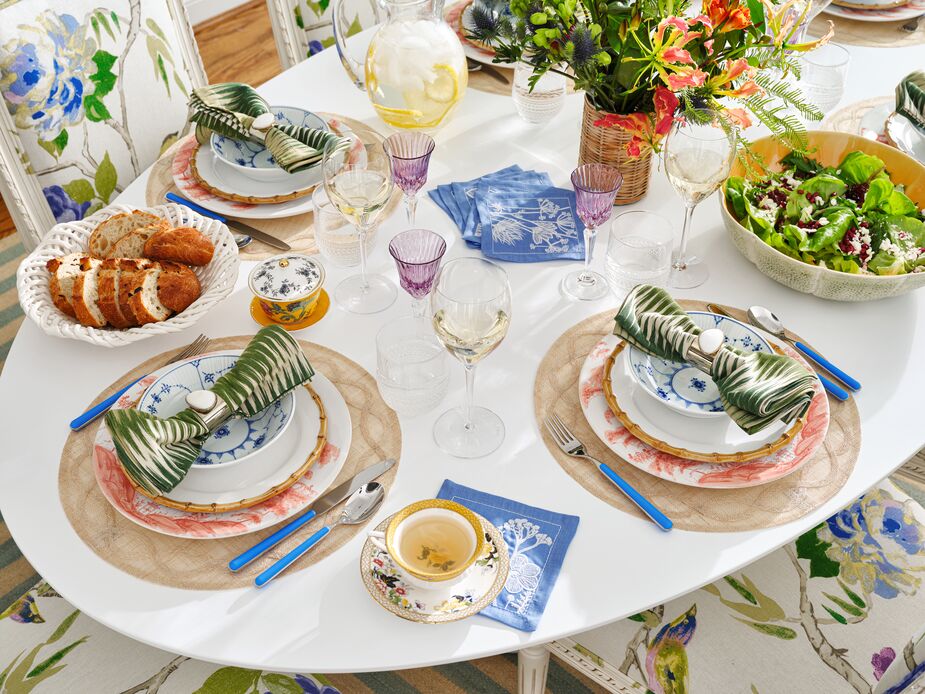 A plain white tabletop or tablecloth is an ideal canvas for layering prints and colors. Start with Tuileries Garden Place Mats in Natural, then add Country Estate Dinner Plates in Petal Pink and salad plates from the Bamboo Place Setting. The blue of the Royal Copenhagen bowls ties in with that of the Sunprint Napkins and the cutlery handles. At the same time, the green Sequoia Napkins complement the exterior of the Melon Fruit Bowl—and with the salad inside it. Photo by Read McKendree.
