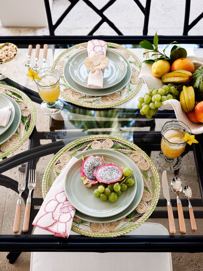 Plain green dishes are made spring-fresh with the addition of fanciful rattan place mats and the Peony Dinner Napkins. The lack of a tablecloth adds a breezy informality (and prevents any real breezes from wreaking havoc.) Find the shatterproof acrylic goblets here, the flatware here, and a similar shell-shape centerpiece here. Photo by Read McKendree.
