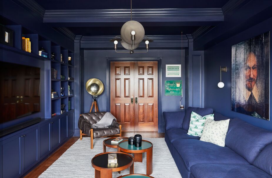 The navy blue provides a dramatic frame to the richly figured walnut doors. The round silhouettes of the lighting serve as a counterpoint to the straight lines that dominate the space.
