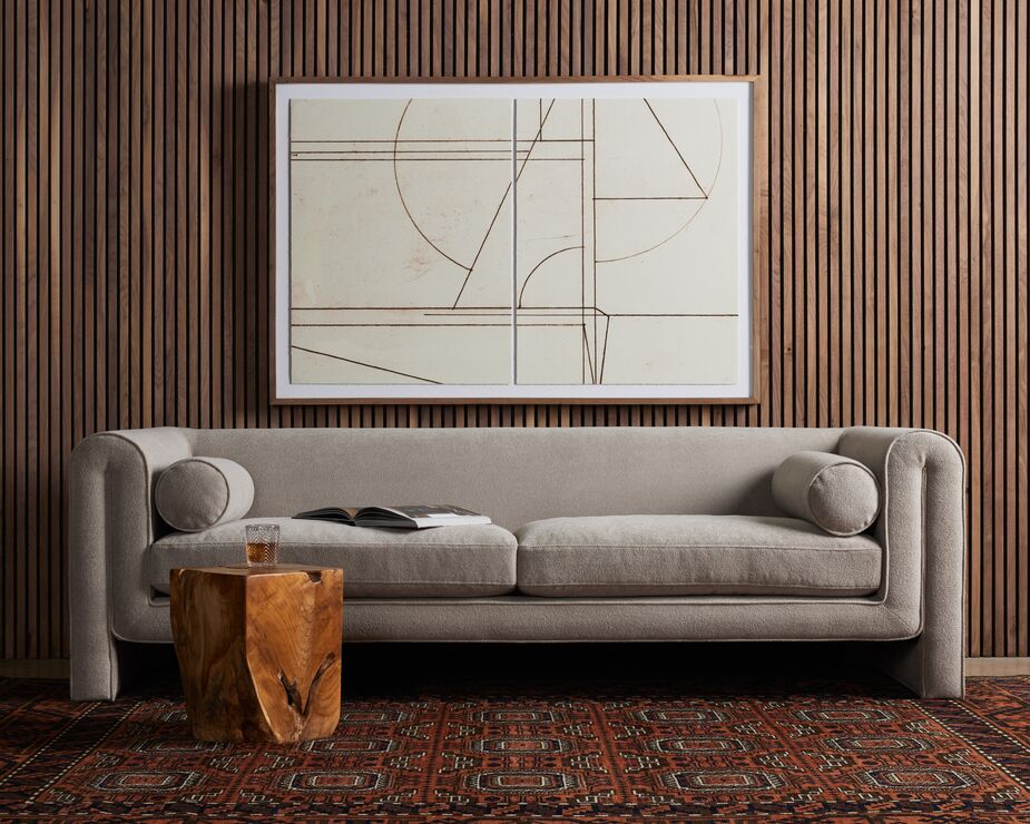 The rounded corners and plush upholstery of the Jess Sofa whisper Art Deco glamour, as does the linear abstract art.
