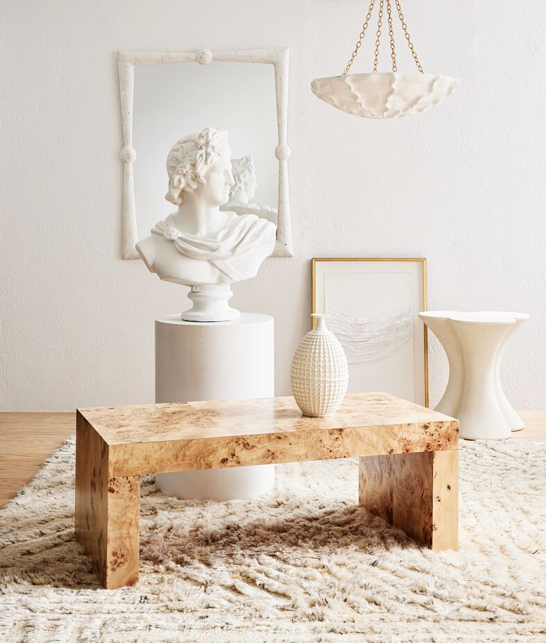 Burl wood and plasterlike finishes complement each other impeccably. Above: Chloe Coffee Table, Scarlett Resin Wall Mirror, Benit Medium Sculpted Chandelier in Plaster White, Carlin Side Table, and Diana Vase. Find the rug here. 
