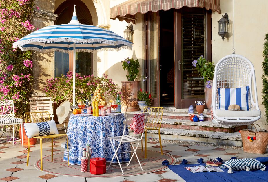 Color, pattern, and fringe: The Ari Pagoda Fringe Umbrella in Regatta Blue has all three. Find the planters flanking the door here and a similar swing chair here. 
