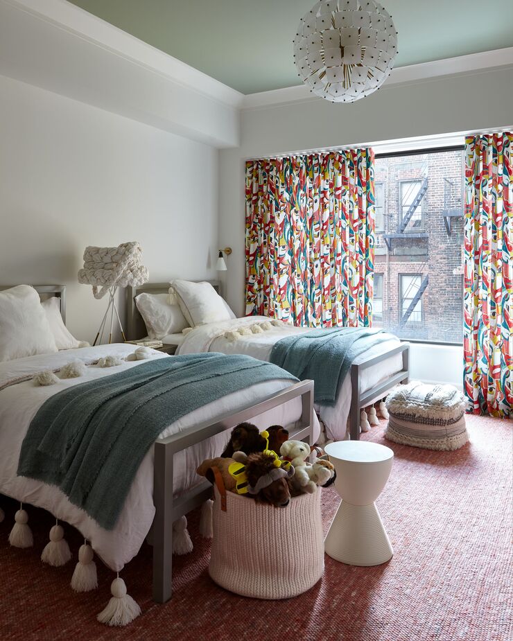 Aside from the kaleidoscopic curtains and the dusky pink rug, the kids’ bedroom was kept fairly neutral so that it could accommodate their changing tastes and interests over time. Find a similar chandelier here. 
