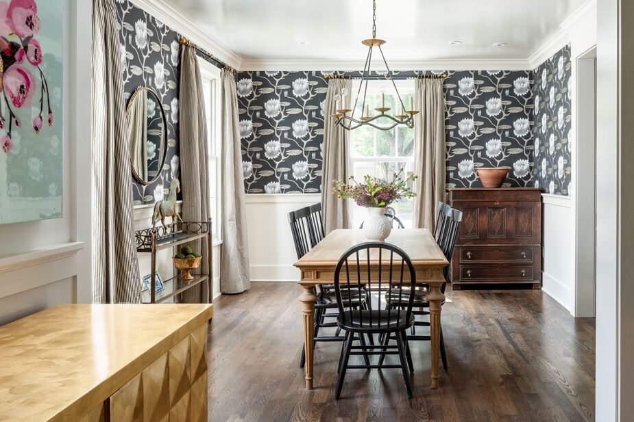 The brown palette of the dining room is an outlier amid the rest of the home’s blues and greens. The large-scale floral print of the wallpaper, however, is consistent with the overall style. The curves of the Choros Chandelier contribute a hint of whimsy. Find similar Windsor chairs here.
