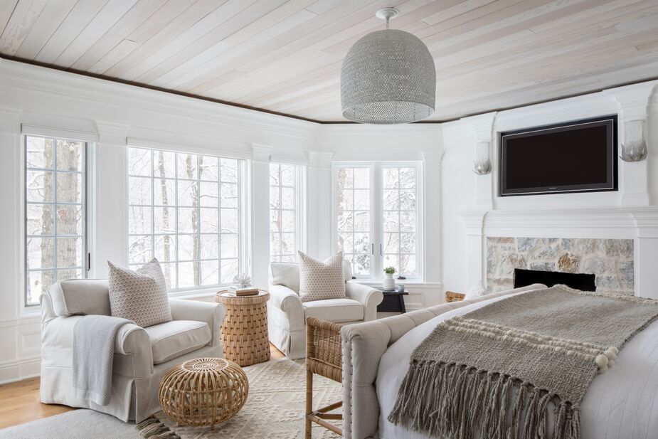 In the primary bedroom, the view is the main attraction, though the stone fireplace and layers of other natural textures are close seconds. Find the ottoman here, the pendant here, a similar rug here, and similar armchairs here. 
