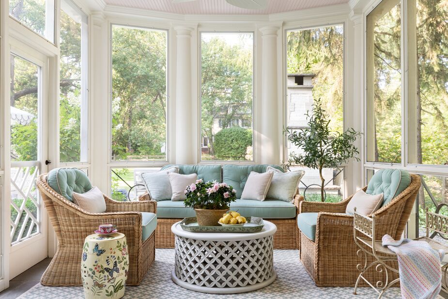 Wicker seating and a butterfly-adorned garden stool give the enclosed porch a summery vibe year-round. Find similar outdoor-suitable chairs here and a coordinating sofa here.
