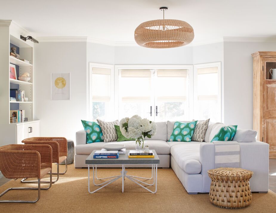 For this Long Island living room, Leslie used natural woven materials throughout—on the chandelier, the stool/side table, the chairs, the rug—to create a relaxed, beachy vibe. “If a room doesn’t feel quite finished, don’t fret,” she writes. “Keep adding layers and accessories from pillows to throws to books on a coffee table and it will fill out.” Photo by Max Kim Bee.
