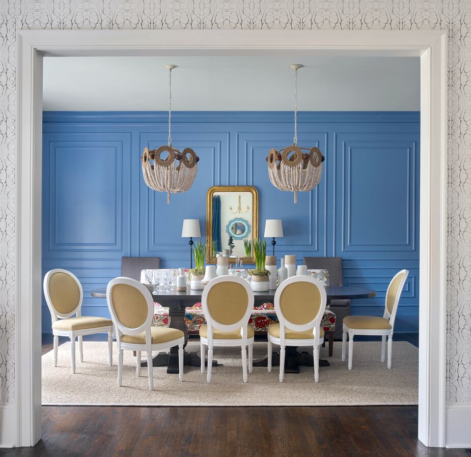 The fresh blue walls, the boho chandeliers, and abstract art, the minimalist chandelier, and the natural-fiber rug add the “new” to this traditional dining room. Find a similar mirror here. Room by Gordon/Dunning; see more of the home here. Photo by Emily J. Followill.
