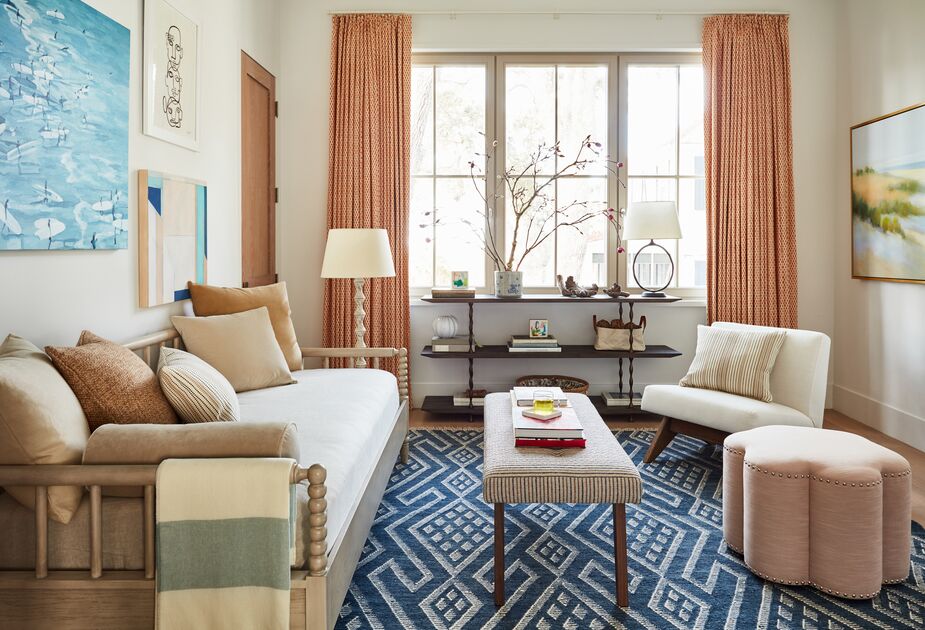 Though space is at a premium in this room, the Gillis Accent Chair and the Kate Ottoman were moved away from the wall, creating the illusion of airiness and drawing attention away from the wall. The ottoman’s scalloped silhouette also distracts from the room’s boxiness, while hanging the curtains well above the top of the windows makes the space feel taller.  

