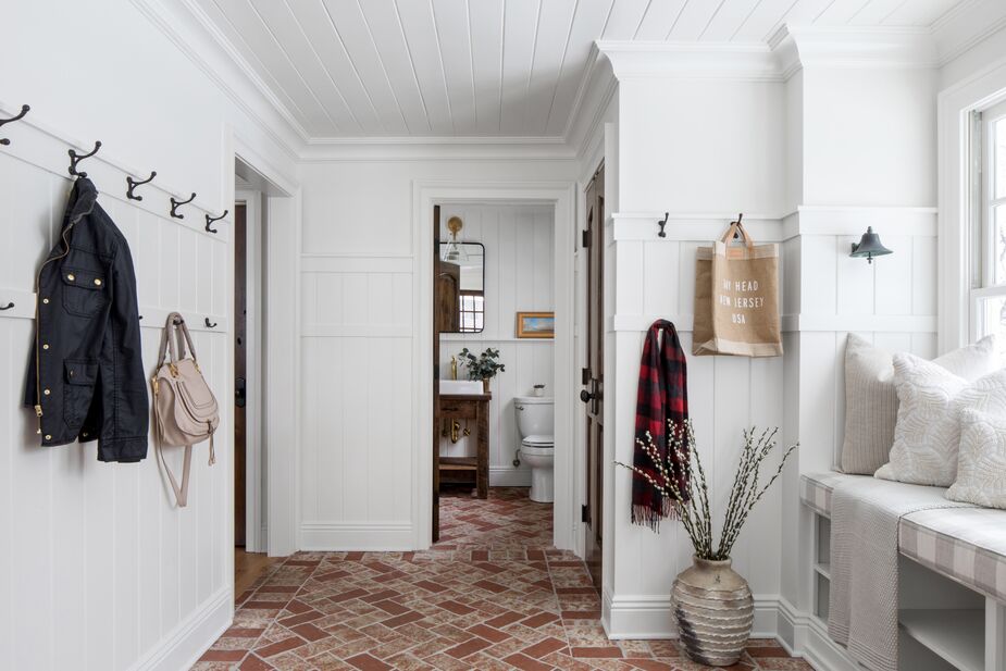 The mudroom and the powder room off the kitchen were taken down to the studs, then renovated with brick floors that are both practical and handsome. The bell beside the window seat, originally in Trish’s house on the Jersey shore, inspired the mudroom’s design. 
