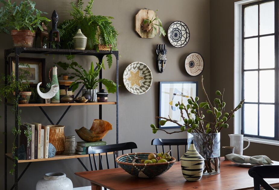Handcrafted African baskets, bowls, jars, and figurines nestle among and beside the myriad plants on the minimalist étagère.
