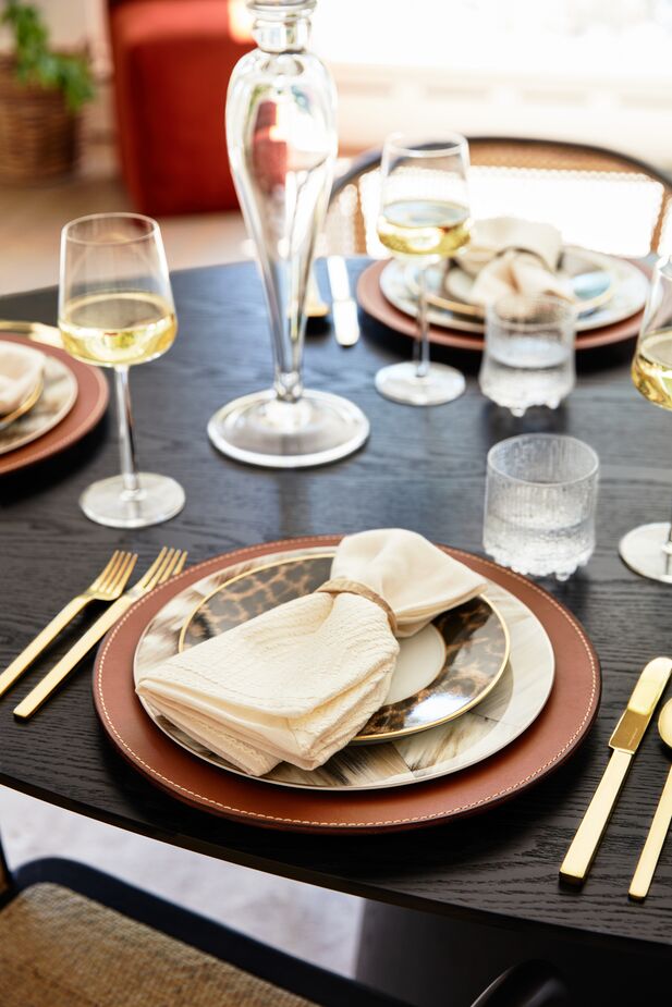 Leather has a place at the table, here in the form of the Wyatt Charger, which speaks to both the luxuriousness of the gold flatware and the earthiness of the leopard-print Hutchinson Salad Plate. Find the water glasses here. Photo by Joe Schmelzer.

