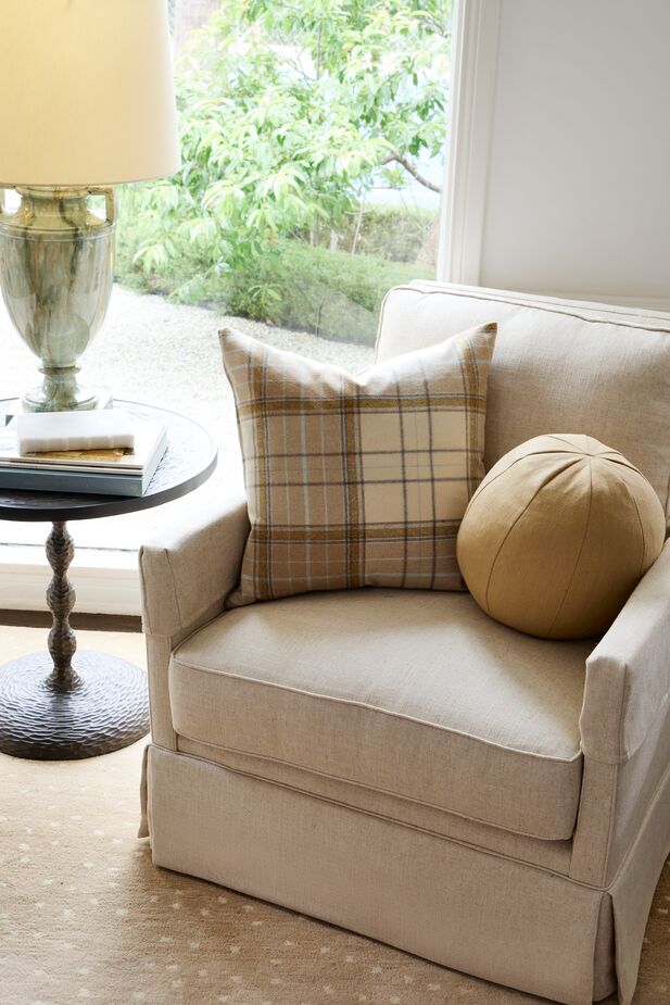 The warm neutrals of the Fauna Rug in Almond and the Emma Ball Pillow in Hemp Linen contribute to this reading nook’s serene vibe. The Caleb Plaid Pillow in Tan/Beige, with its pale blue stripes, and the muted greens of the Kensington Table Lamp add subtle color.
