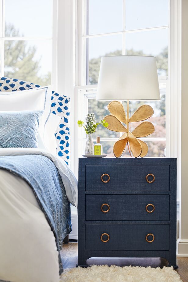 This room encompasses both organic ease and everyday glamour by homing in on blue and gold as the common denominators. The Kos 3-Drawer Raffia Nightstand in Navy brings natural fibers into the room but complements them with golden drawer pulls. The Jane Petal Table Lamp in Gold Leaf has a glamorous glimmer, but the shape is beautifully organic. Also shown: the Trinka Upholstered Bed in Navy. Photo by Joe Schmelzer.
