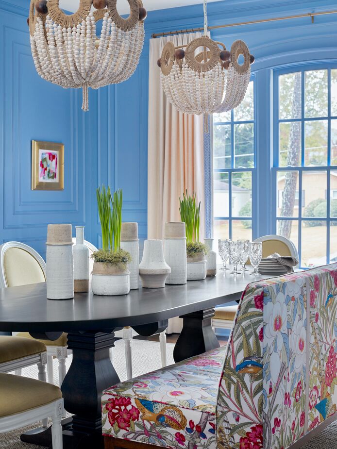 The wooden beads of the chandeliers and the collection of stoneware vessels on the table accentuate the dining room’s joie de vivre. Find a mirror similar to the one in the top photo here.
