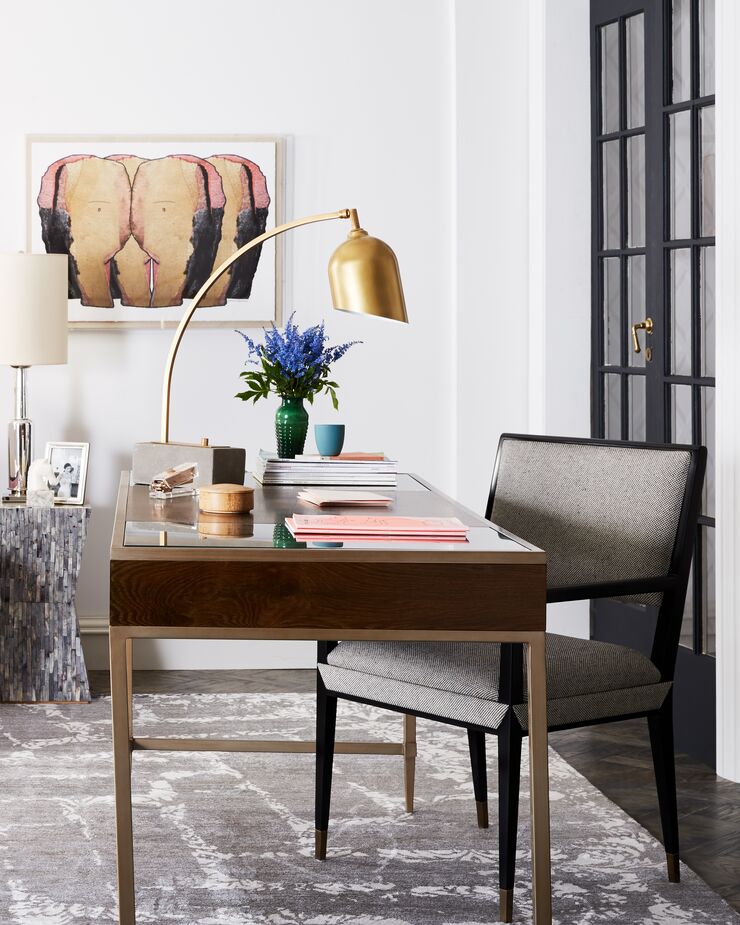 The slender tapered legs of the chair bring MCM ease to this Curator-style office, as do the brass finish of the desk’s open base and of the arched task lamp. 
