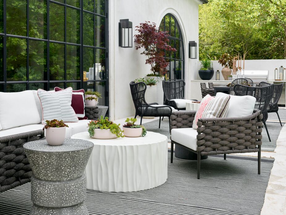 To avoid distracting from the verdant surroundings, Shelby Adamson of Little Black Fox opted to keep the upper patio monochromatic. The wealth of textures more than makes up for the tight palette, however. Rugs help delineate the lounge and dining areas. Find similar sconces here. 
