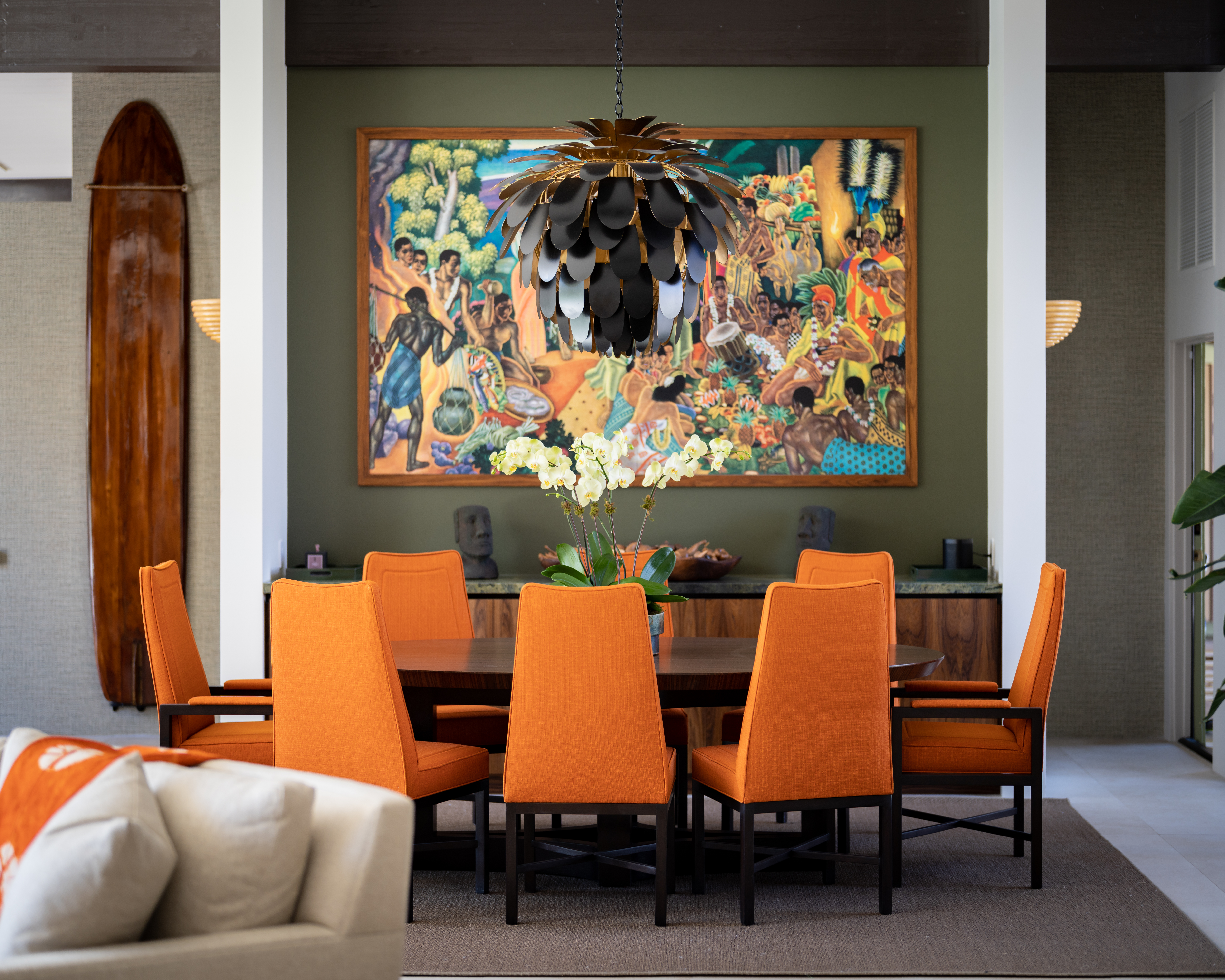 The green-and-orange palette of the family room continues in the dining room by Michael Berman of Michael Berman Ltd., the show home’s lead designer. Surrounded by walls clad in pale grass cloth, the olive-green alcove wall draws attention to the reproduction on ceramic of Eugene Savage’s 1940 mural Island Feast and to the carvings displayed on the marble top of the built-in sideboard. Find a similar lighting fixture here.
