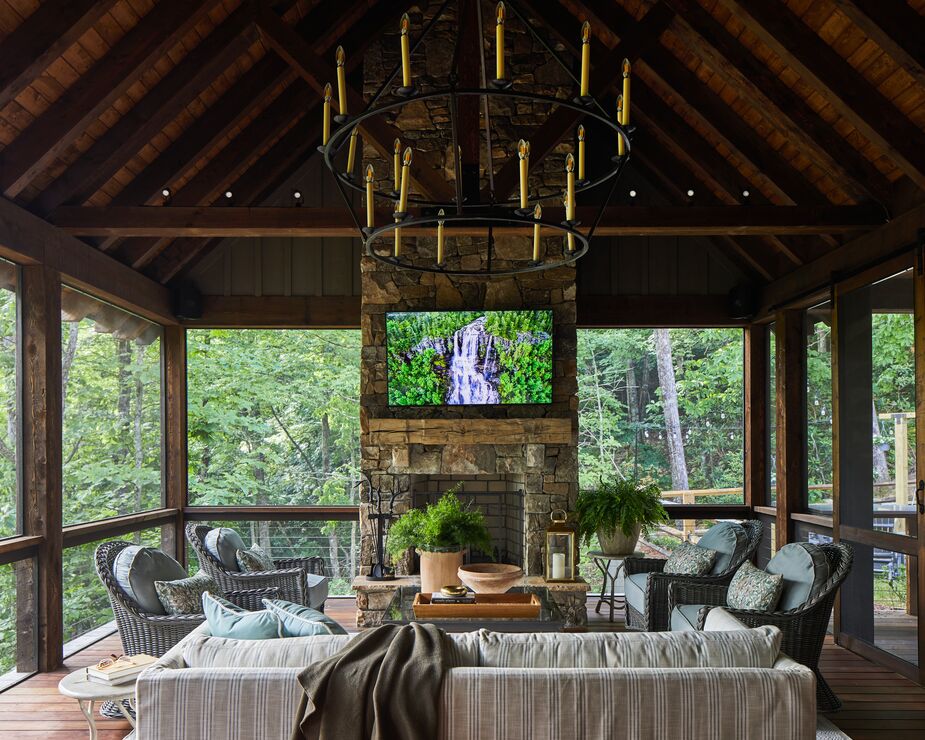 A bold Visual Comfort chandelier and easy slipcovered sofas make the screened-in porch a comfortable, inviting space.
