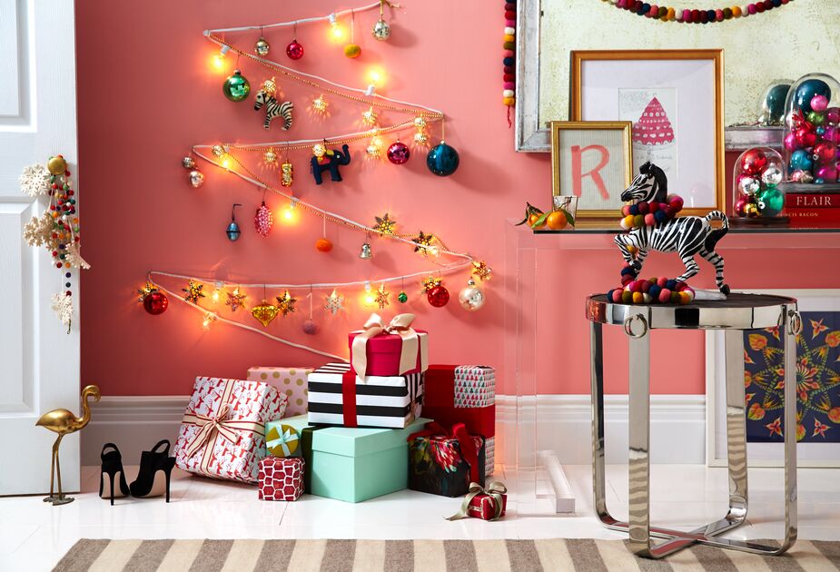 No tree? No problem! Attach string lights, tinsel, ribbon, or rope to a wall in a zigzag pattern reminiscent of an evergreen tree, then hang ornaments from it. We also love displaying ornaments in a cloche, as seen on the console table above. Photo by Jason Hamilton.
