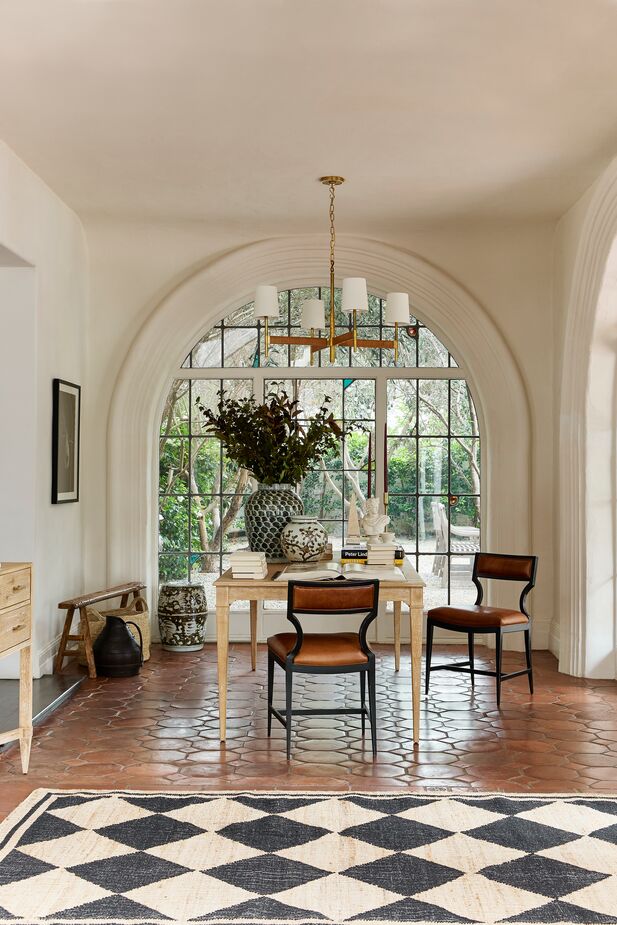 The dark frames and leather of the Raylan Leather Chairs provide a Spanish-influenced complement to the lime-washed finish of the Sarah Extension Dining Table. Also shown: the Elle Large Rattan Chandelier and the Orchard Diamond Rug. Photo by Matt Albiani.
