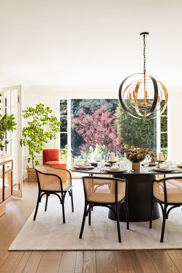 The rattan seats and cane inserts of the Tate Rattan Armchairs in Black/Natural nod to Naturalist ease, but the Belle Époque curves put these chairs in the Curator camp. The Luna Chandelier provides a luxurious top note.  Find the dining table here and the rug here. Photo by Joe Schmelzer.
