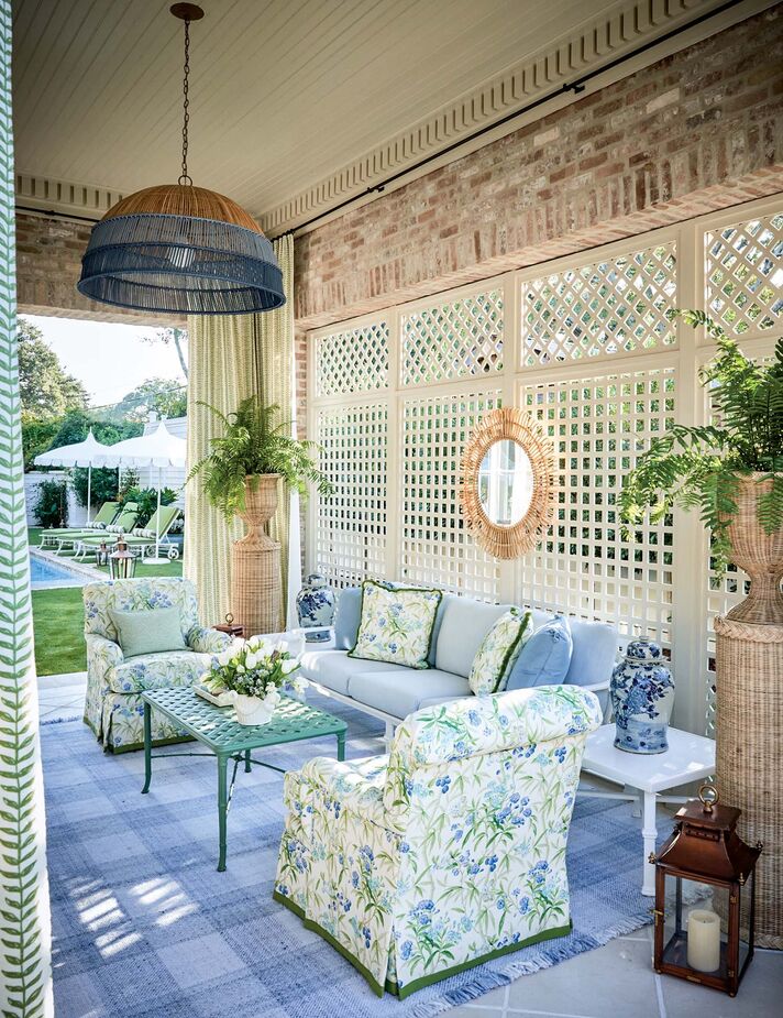 The covered porch designed by Will Huff and Heather Dewberry Stoller of Huff-Dewberry is a rhapsody in blues—and greens and rattan. The gridded insert of the side window lets in just enough sunshine while also providing shade—important in a Southern locale.
