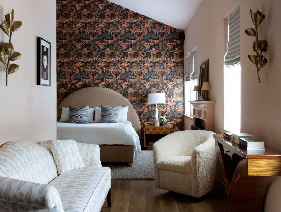 A wall was opened up to give the client a sitting area by the primary bedroom’s fireplace. Vintage nightstands flank the custom bed. Find a similar bouclé chair here. 
