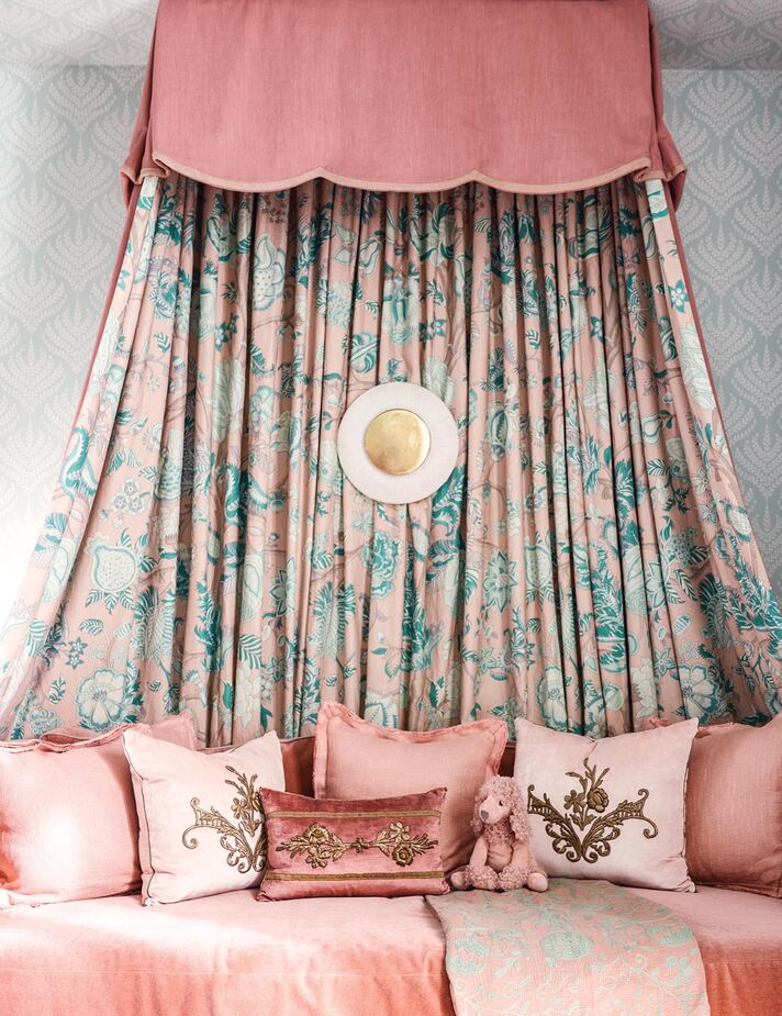 This nursery by Kara Cox is certain to appeal to parents as well as babies. In fact, they might want to maintain this sumptuously layered daybed long after their little one has outgrown a crib. The green of the wallpaper and the fabric prevents the bouquet of pinks from feeling too precious.
