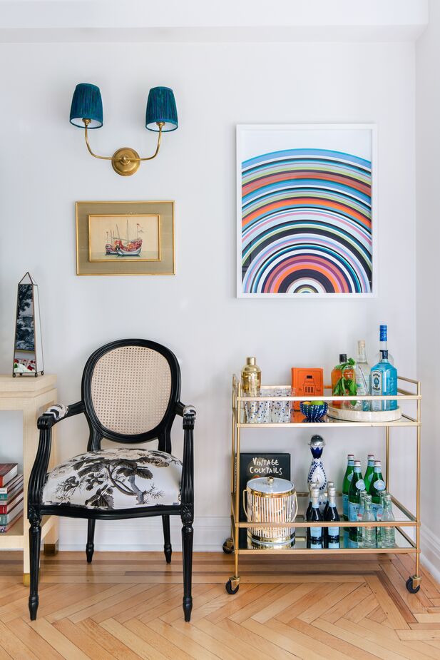 Hanging above the bar cart is Santa Monica by Dawn Wolfe. As well as tying in with the rainbow of colors in the living room, “it adds the perfect modern twist to my otherwise traditional art,” Libby notes. Like the Wolfe piece, the vintage ice bucket is from One Kings Lane.
