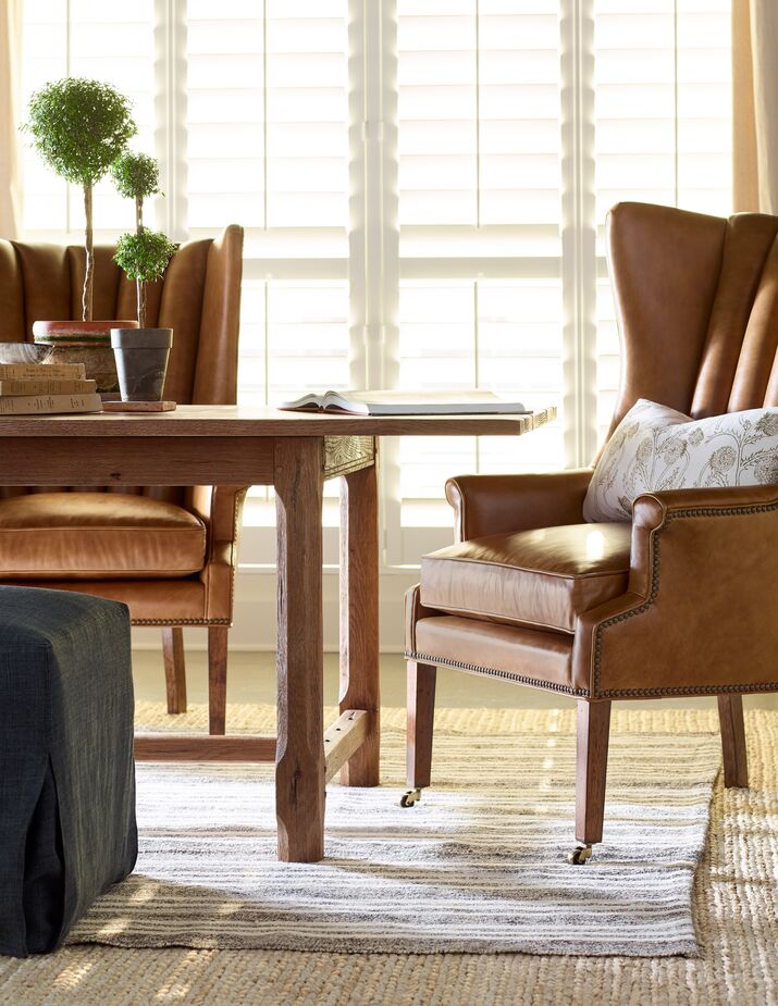 Brass nailheads accentuate the silhouette of the Philosopher Leather Wing Chair as well as complement the casters. Also shown: the Forever Extension Dining Table.
