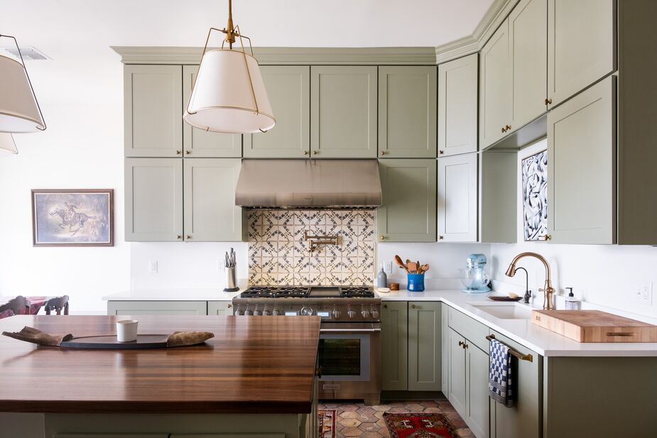 Vintage runners are layered atop the reclaimed terracotta floor tiles from France. The backsplash tiles are by Lauren Liess (you can find her furniture and art here). Art above the sink makes up for the lack of a view when washing up.
