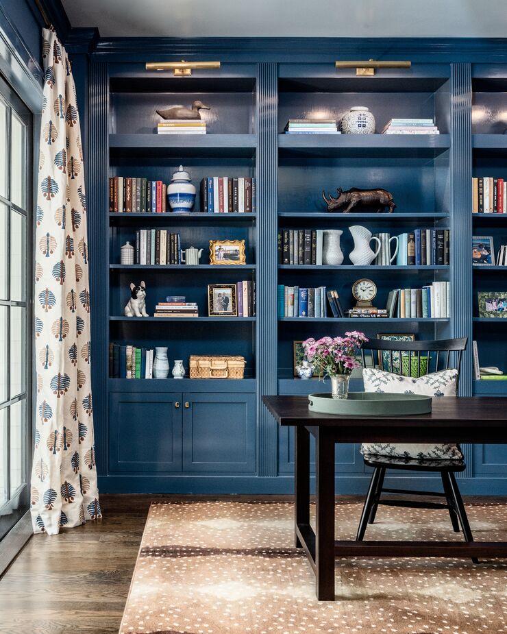 Dark blue lacquered built-ins signal that this room is designed for business, but the frond-print curtains and the animal-print rug keep things from becoming somber. Find a similar rug here. 
