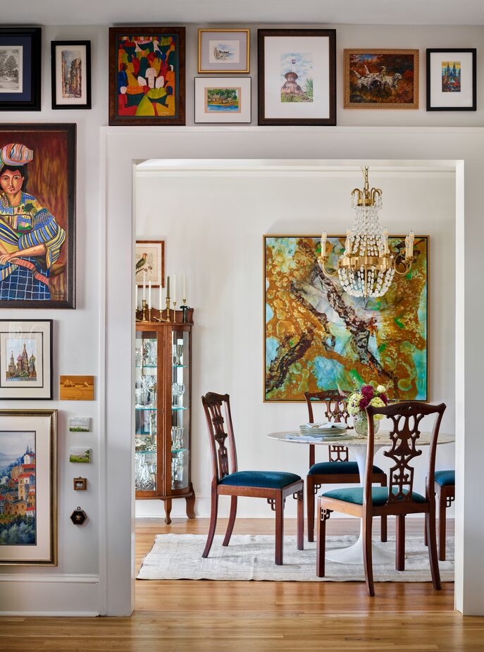 The dining room is an olio of styles, with an Empire-influenced chandelier from Visual Comfort sparkling above chairs from an estate sale and a Tulip-style table. The abstract painting is by John Ishmael, whom Lathem once worked for. 
