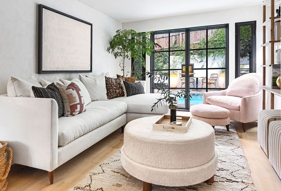 A cornucopia of curves, rounded corners, and plush textures take the edges off this room. Find the sectional sofa here, the faux-shearling ottoman here, the armchair here, and its matching footstool here.
